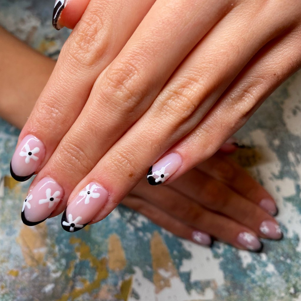 An image of one of my clients manicures. This is a plexigel overlay with a black french tip shellac with white flowers dotted randomly around each nail.